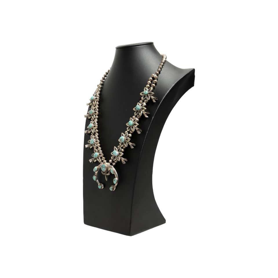 Alt Text: Vintage Navajo flower blossom squash necklace with turquoise stones and sterling silver flower motifs on a black display bust, featuring double strand design and naja pendant.
